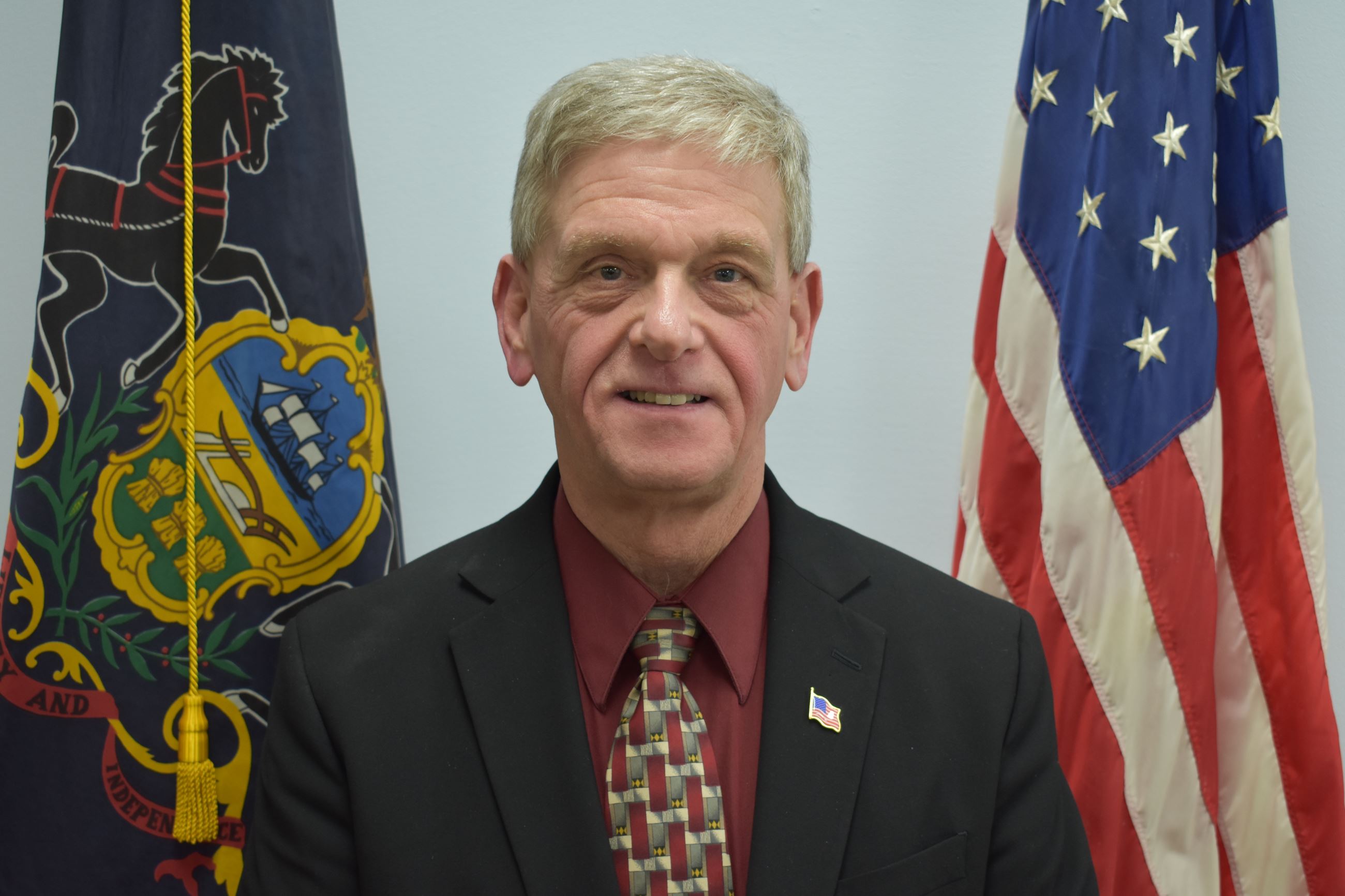 Photograph of Commissioner Tom Hempel with Flags in the Background