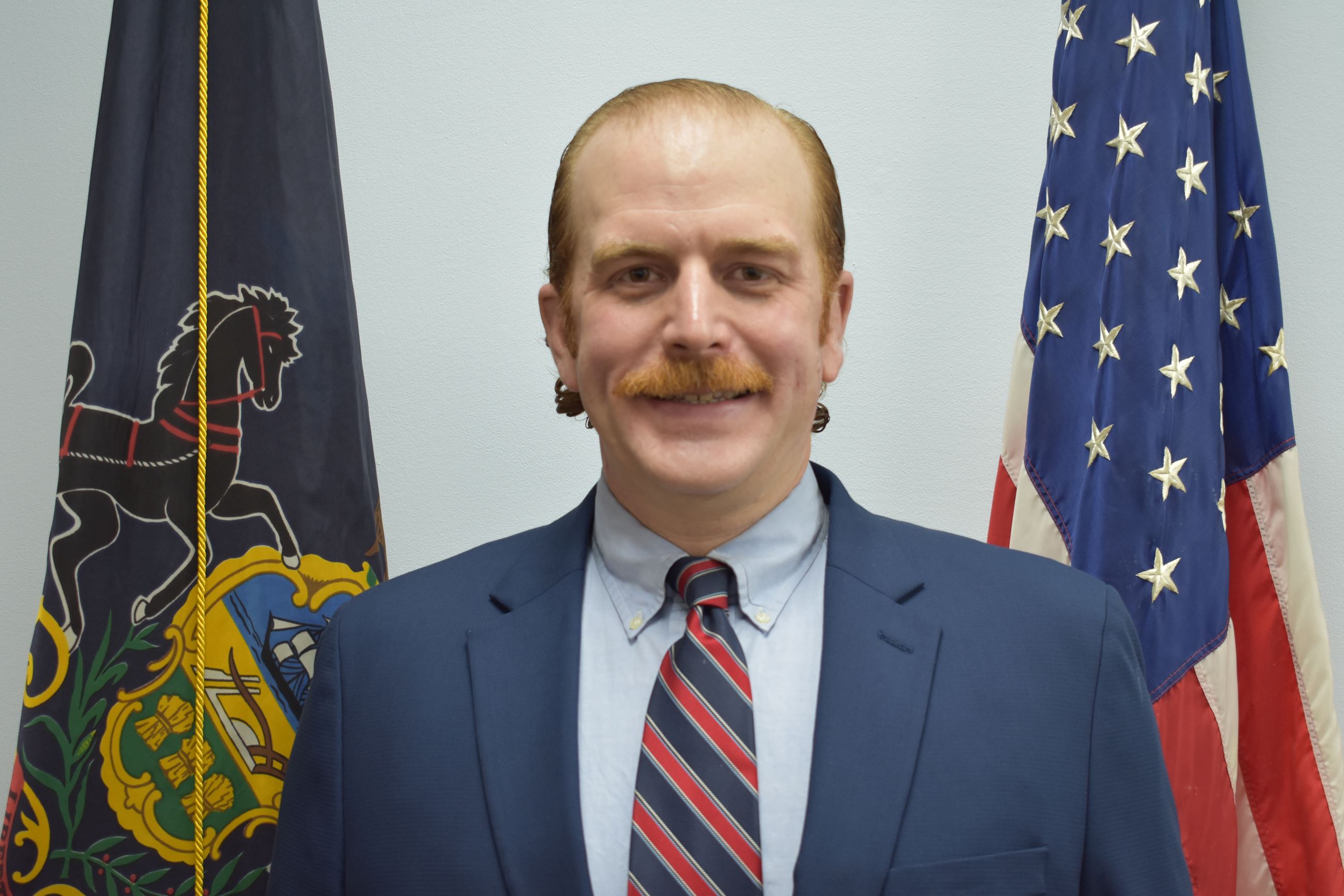 Photograph of Commissioner Zachary Haigis with Flags in the Background